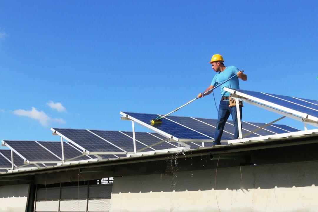 A man standing on top of a building near some solar panels.